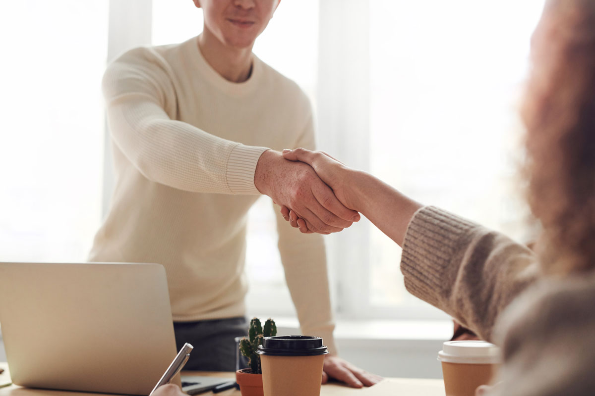 business man in white sweater shaking hands with woman
